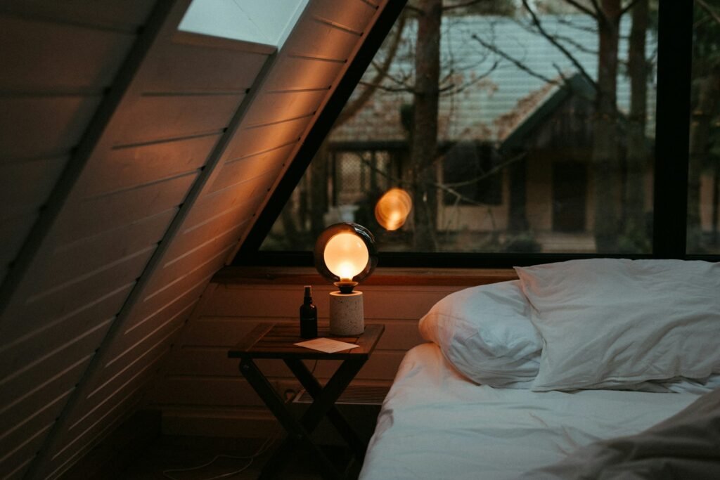 Small bedroom lit by a warm bedside lamp