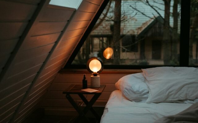 Small bedroom lit by a warm bedside lamp
