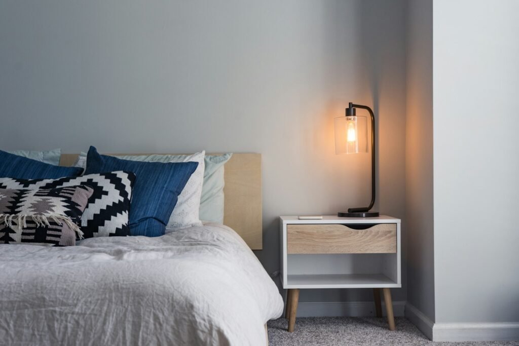 Black table lamp on a nightstand next to a bed